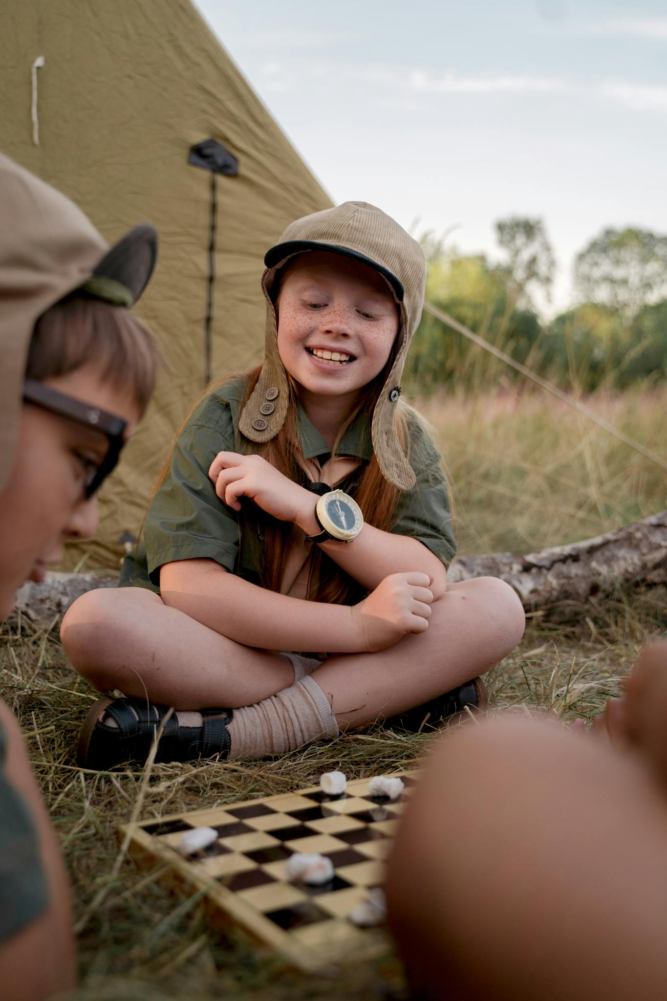 Young scouts playing chess outdoors, embracing adventure at a campsite.